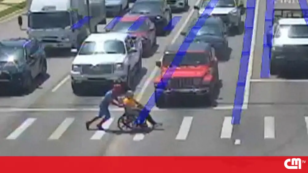 Homem vestido de Homem-Aranha ajuda pessoa em cadeira de rodas a atravessar a rua